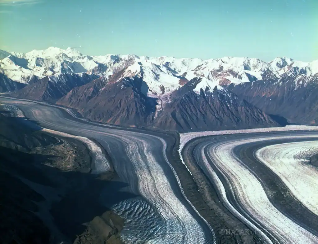 Glacial landscape with snow-capped mountains and winding ice formations.