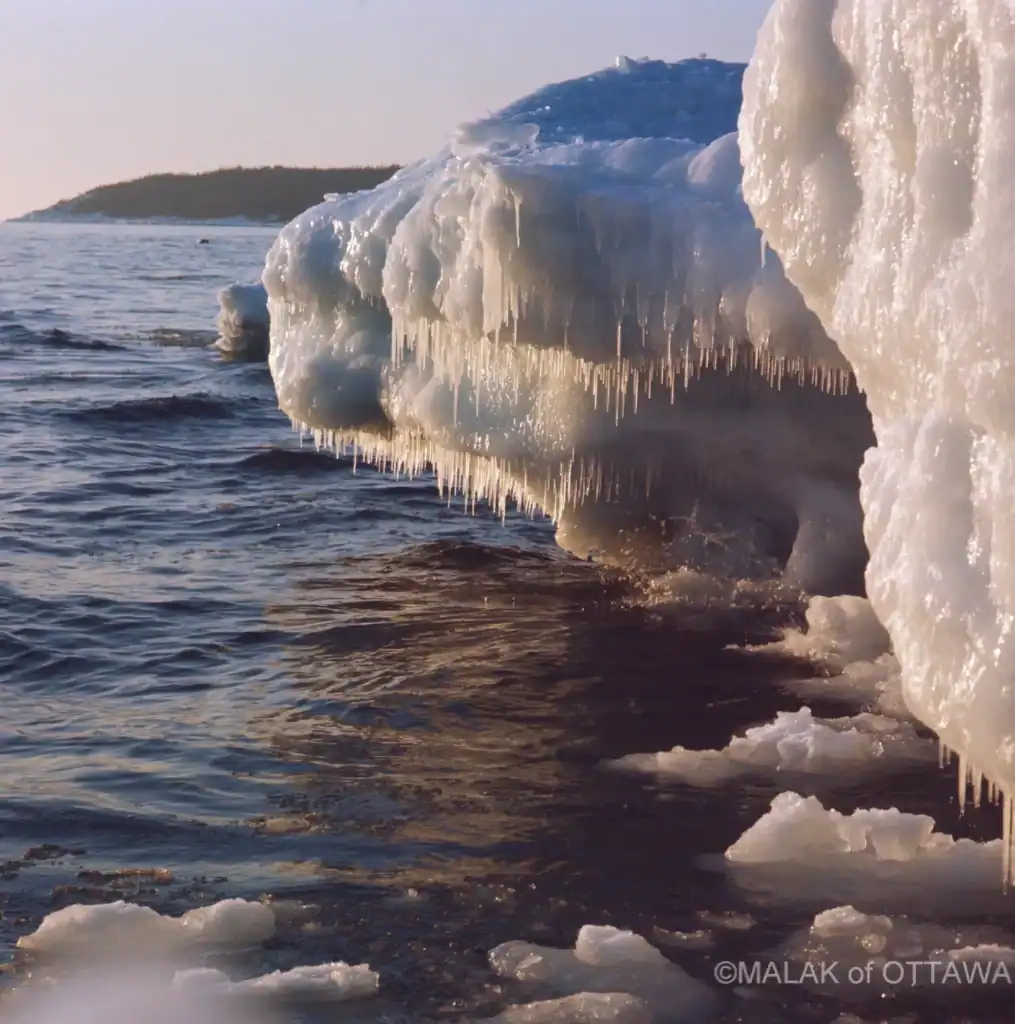 Ice-covered rocks and icicles along the shoreline.