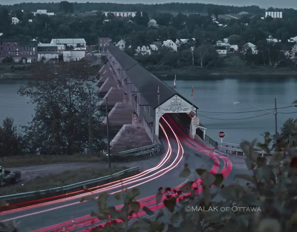 Ottawa historic Rideau Canal bridge with light trails and cityscape background.