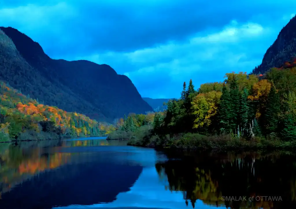 Scenic river view with mountains and colorful autumn trees.