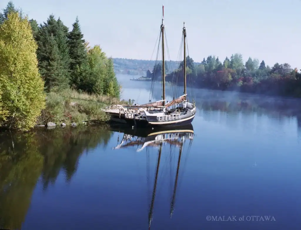 Boat on peaceful river surrounded by trees in Ottawa, Canada.