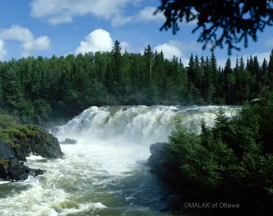 Pisew Falls in Ontario with lush green trees and flowing water.