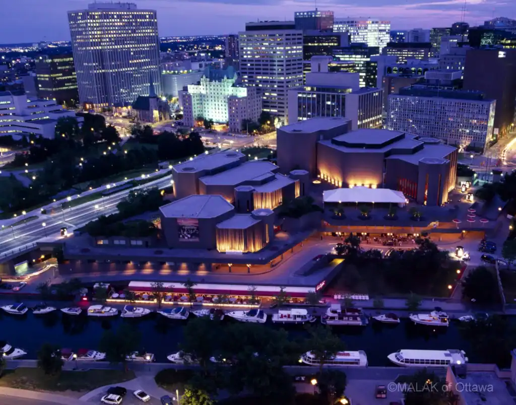 Night view of Malak of Ottawa restaurant illuminated in downtown Ottawa skyline.