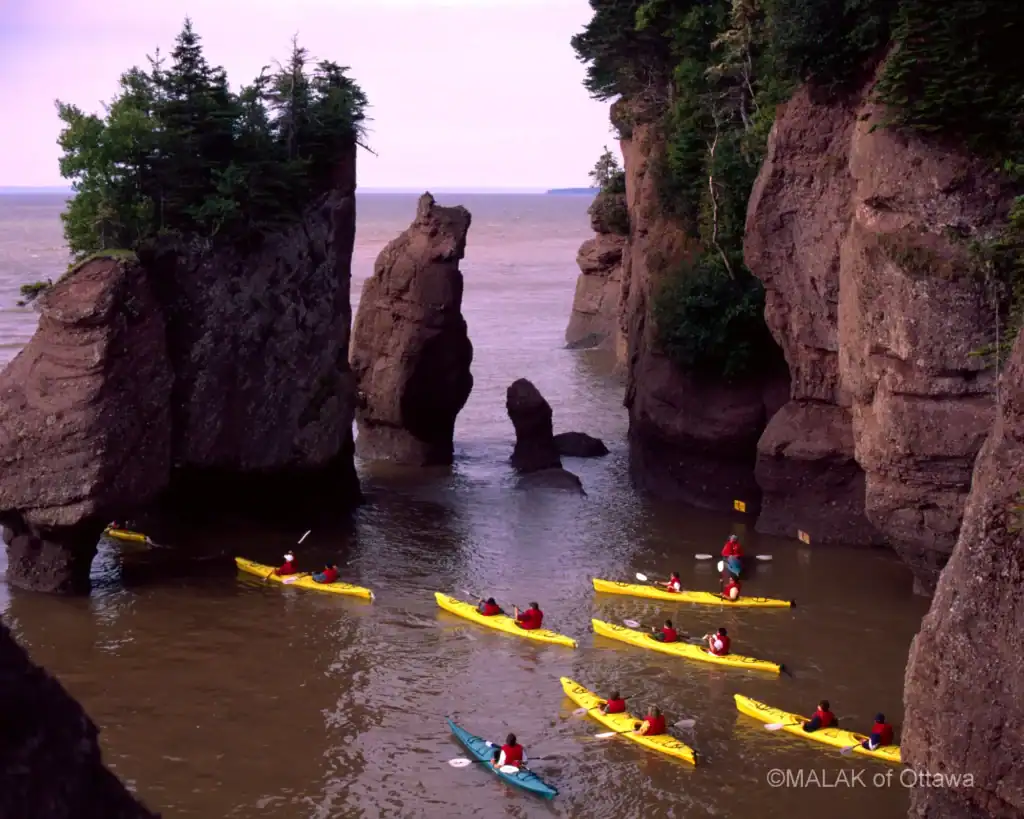 Kayakers exploring the scenic sea caves at Malak of Ottawa. Experience stunning coastal views and ou.