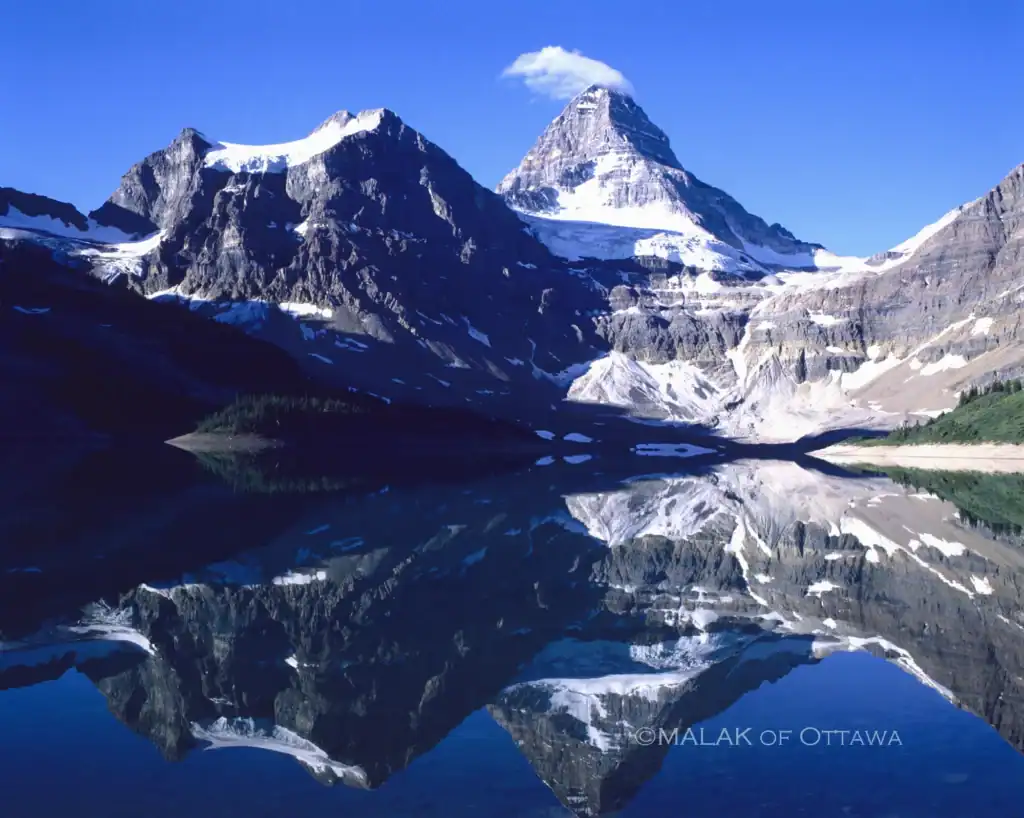 Majestic mountain landscape with snow-capped peaks reflected in a calm lake.