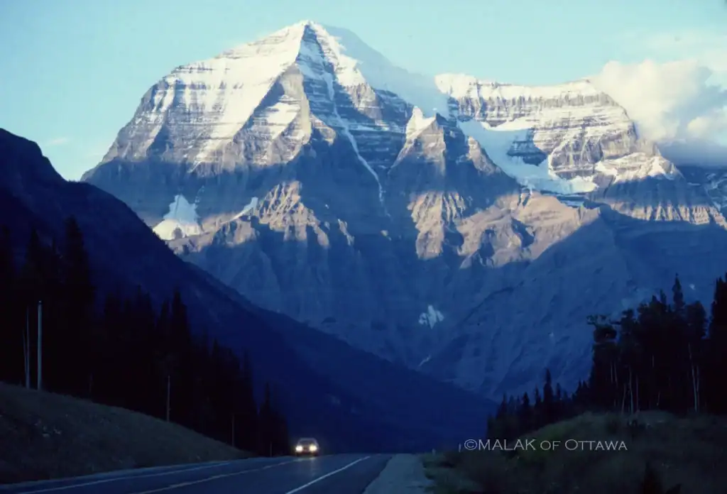 Snow-capped mountain peaks with a scenic highway in the foreground.