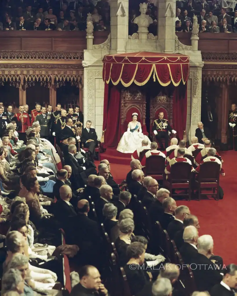 Formal royal event with audience and regal figures on stage.