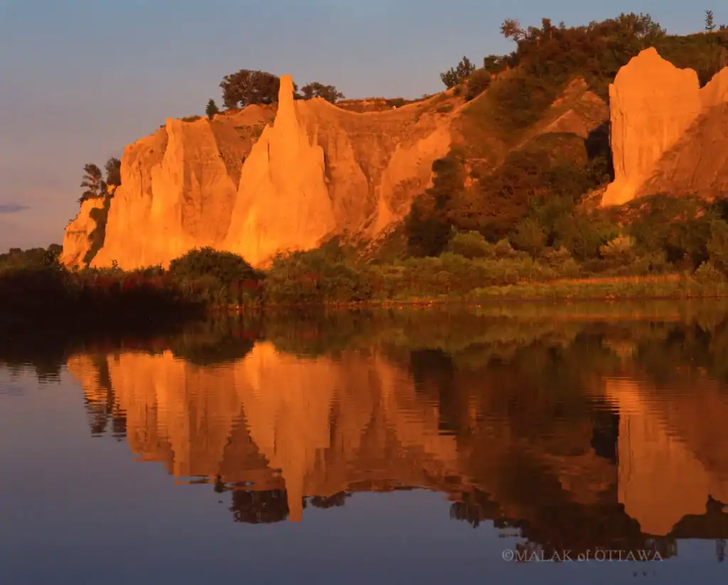 Sunset over the striking cliffs along the Ottawa River, showcasing natural beauty and vibrant orange.