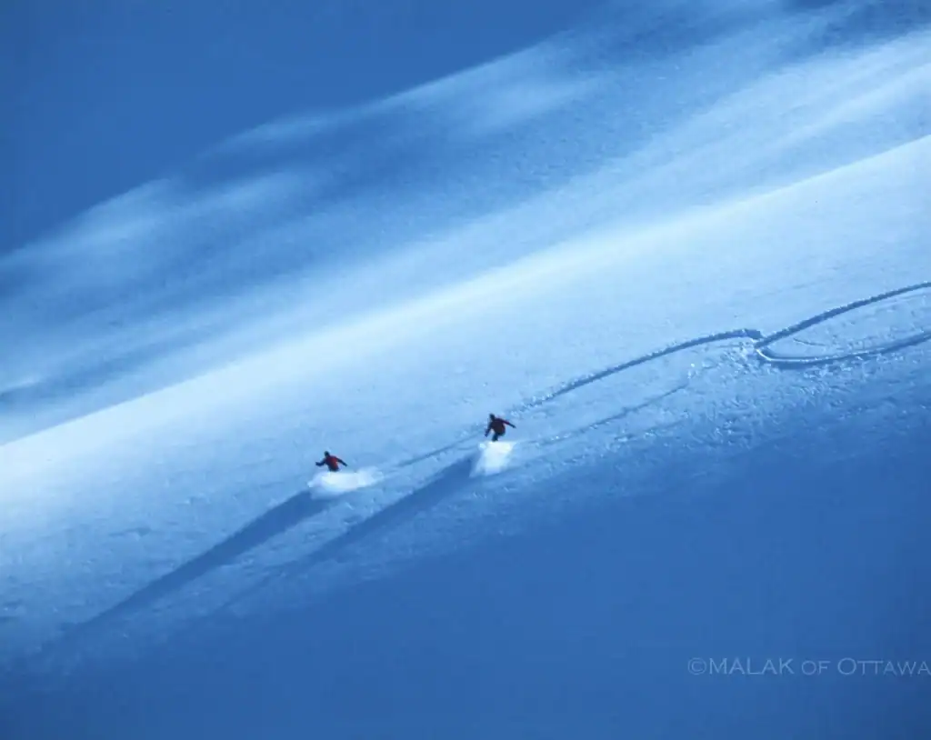 Skiers enjoying fresh powder snow on a mountain slope.