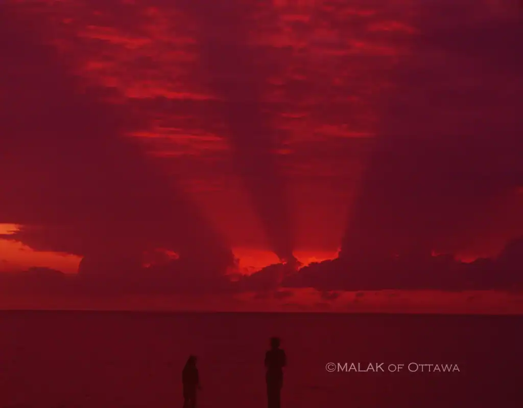 Sunset over the ocean with vibrant red and orange hues illuminating the sky.