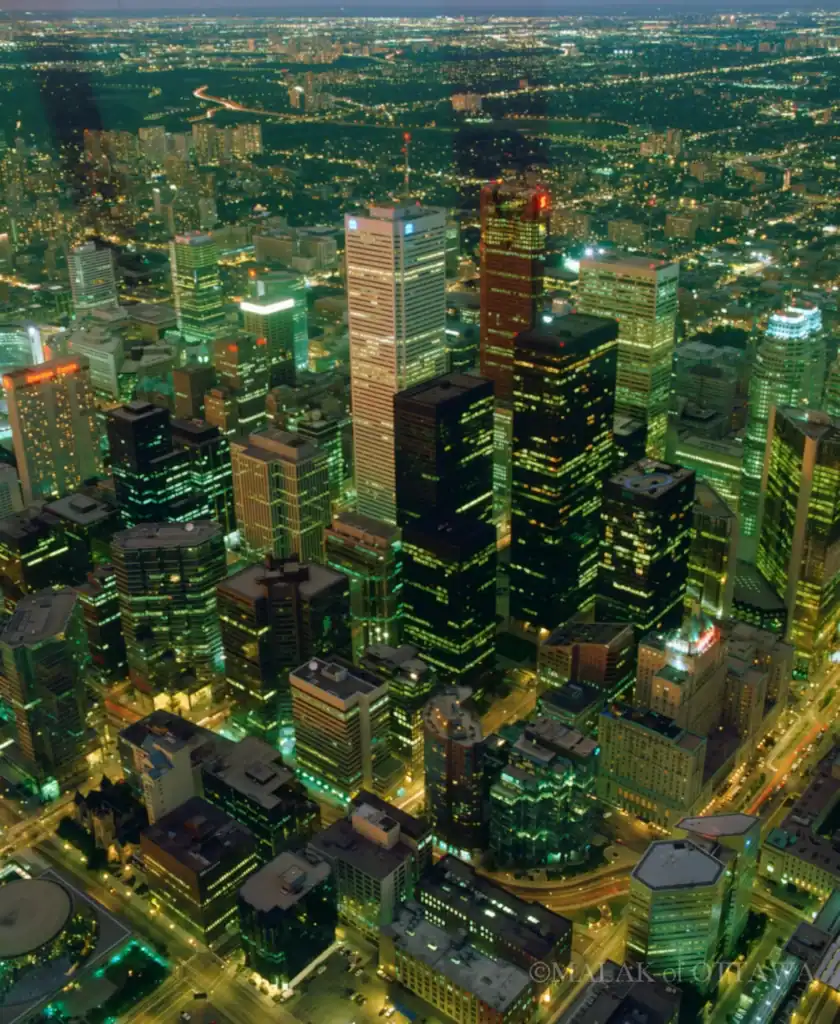 Night view of Toronto's downtown skyscrapers illuminated with vibrant green and yellow lights.