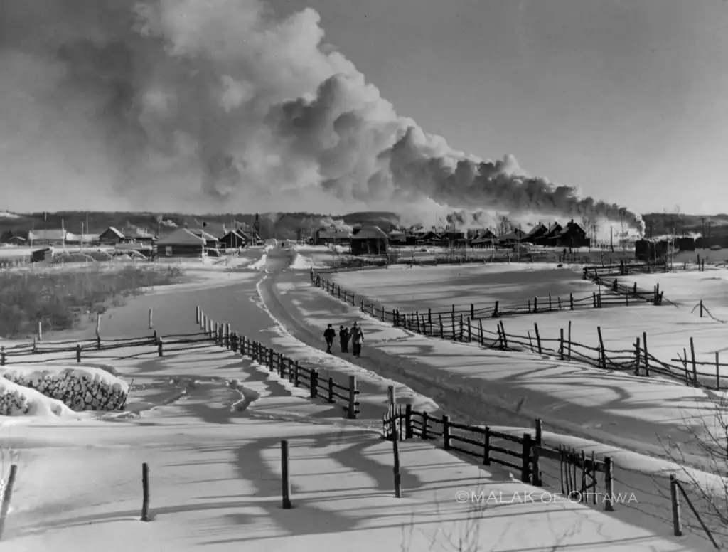 Snowy winter scene in Ontario with walking paths and industrial smoke.