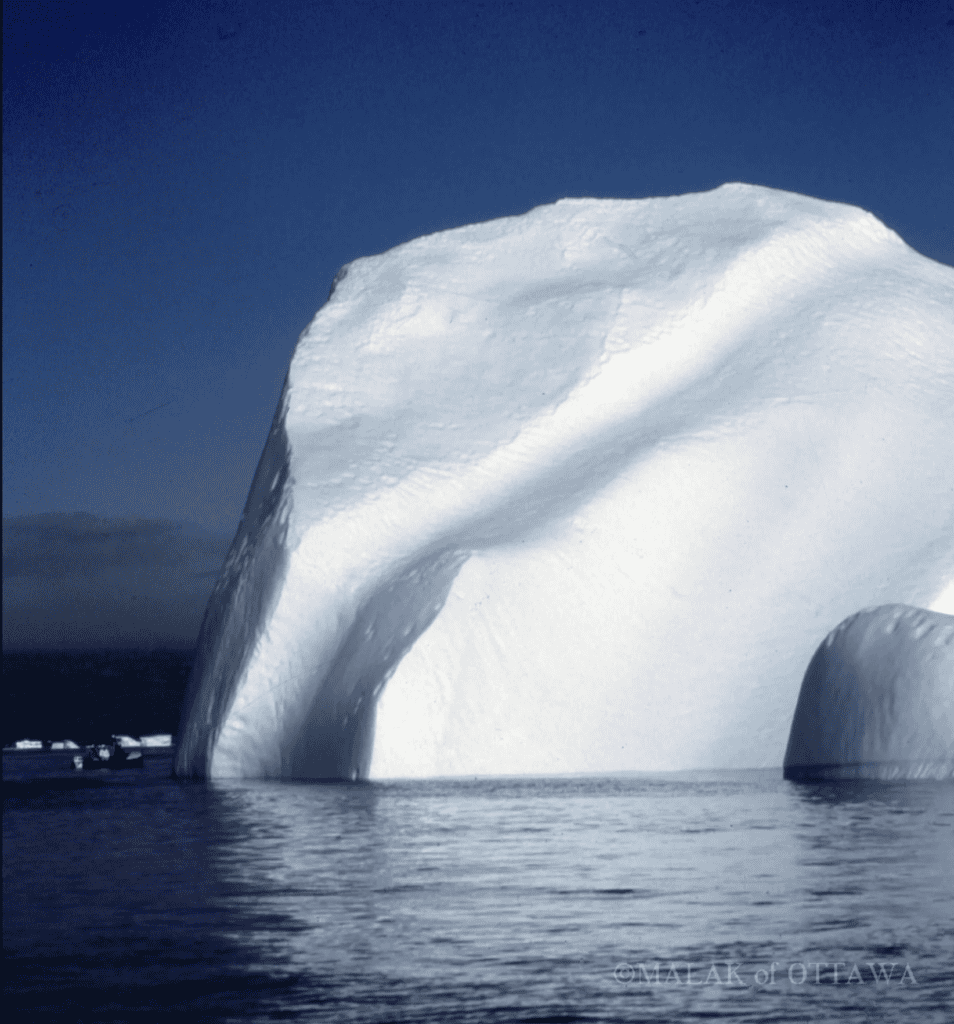 Iceberg floating in cold Arctic waters with a clear blue sky.